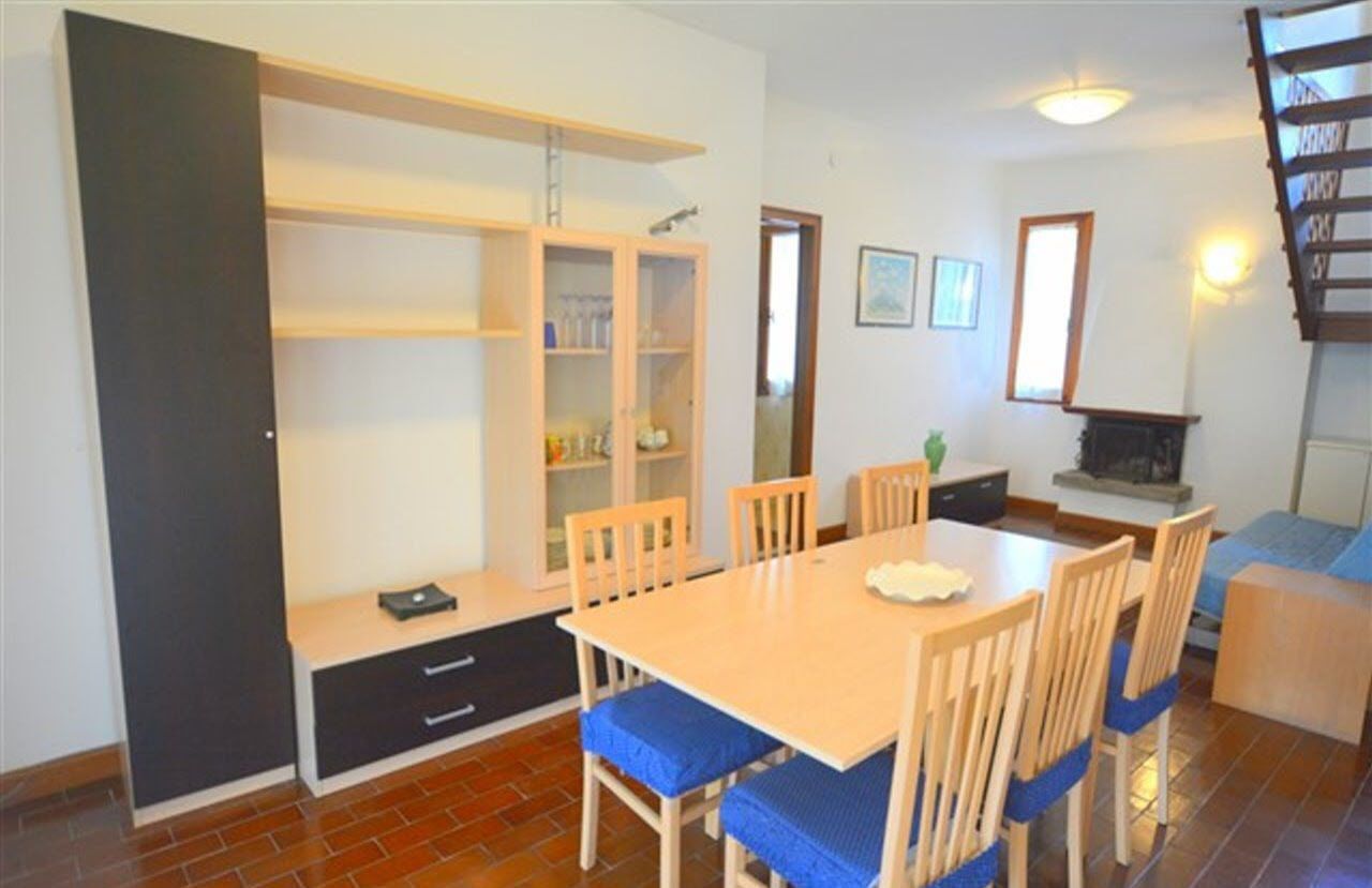 Un comedor con una mesa y sillas de madera, una estantería y una chimenea.
