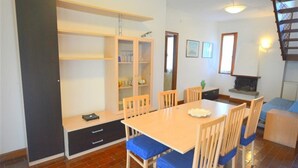 Ein Essbereich mit einem Holztisch, Stühlen, einem Bücherregal und einem Kamin.
