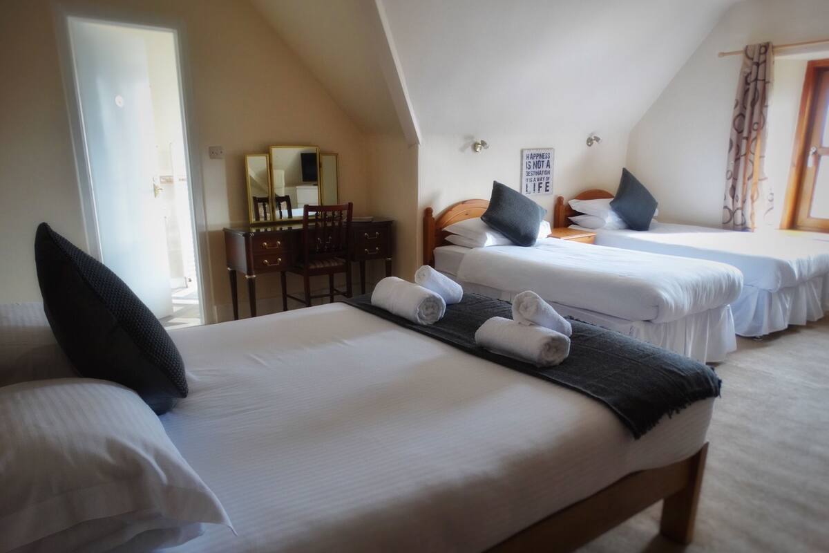 A hotel room with two beds, a desk, and a mirror.