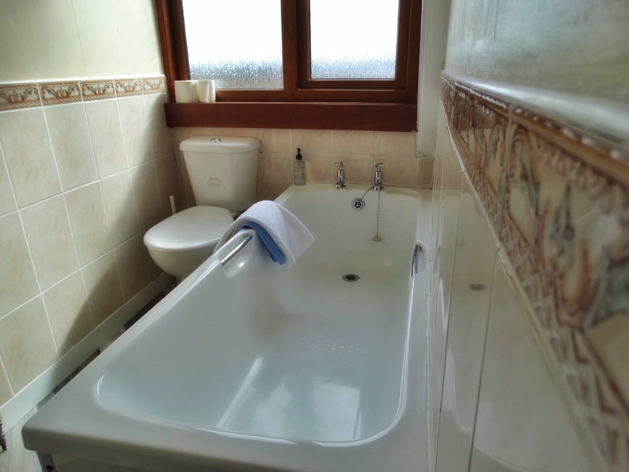 A bathroom with a bathtub, toilet, and window.