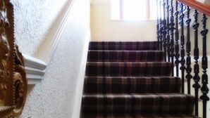 A staircase with a checkered carpet and black balusters. - Kilchoan House Hotel (Acharacle)