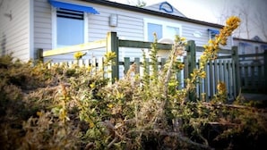 Une maison mobile entourée d’une clôture en bois et bordée d’une végétation luxuriante.