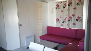 Une pièce avec un canapé rouge, une petite table et une armoire blanche.