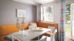 Une pièce moderne avec une table blanche, un canapé orange et une fenêtre agrémentée de rideaux à motifs.
