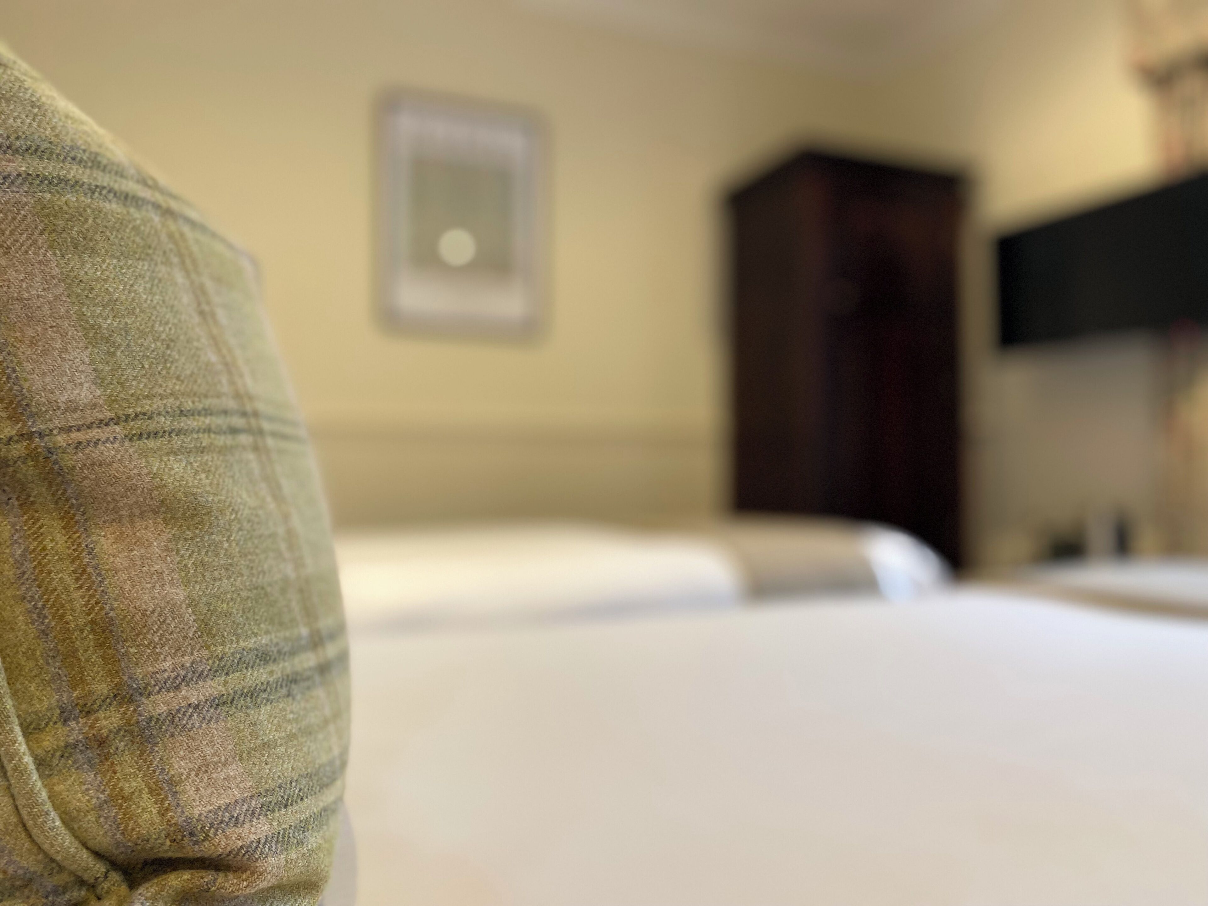 Una habitación de hotel con una cama, un armario y un televisor en la pared.