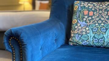 Un canapé bleu avec un coussin à motifs floraux et une bordure ornée de perles.