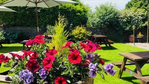 A garden with a wooden picnic table and a white umbrella. - Middle House (Leyburn)