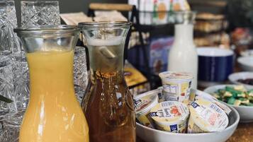 Ett bord med olika sorters mat, inklusive en kanna med apelsinjuice, en flaska mjölk och förpackningar med yoghurt.