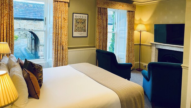 A hotel room with a bed, two chairs, a TV, and a fireplace. - Middle House (Leyburn)