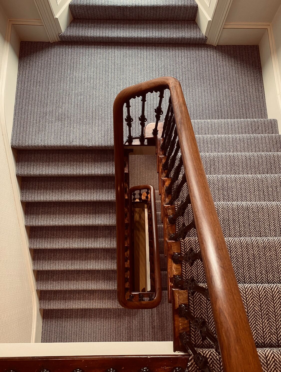 Una escalera con barandilla de madera y un suelo con diseño.