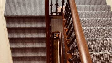 Una escalera con barandilla de madera y un suelo con diseño.