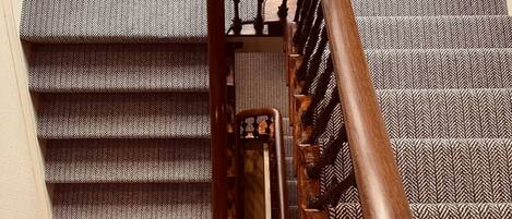 Una escalera con barandilla de madera y un suelo con diseño.
