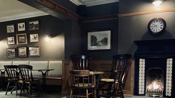 A room with a fireplace, framed pictures on the wall, and wooden furniture.