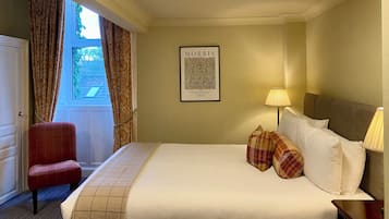 Ein Hotelzimmer mit einem Bett, zwei Nachttischlampen, einem Sessel, einer Tür und einem gerahmten Zitat an der Wand.