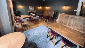 A cozy room with a wooden dining table, chairs, and a bench. There is a fireplace with a framed picture above it. - Middle House (Leyburn)