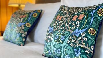 Una cama con dos almohadones decorativos con motivos florales y de pájaros.