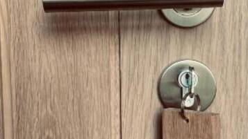 A wooden door with a metal handle and a keycard with the number 8.