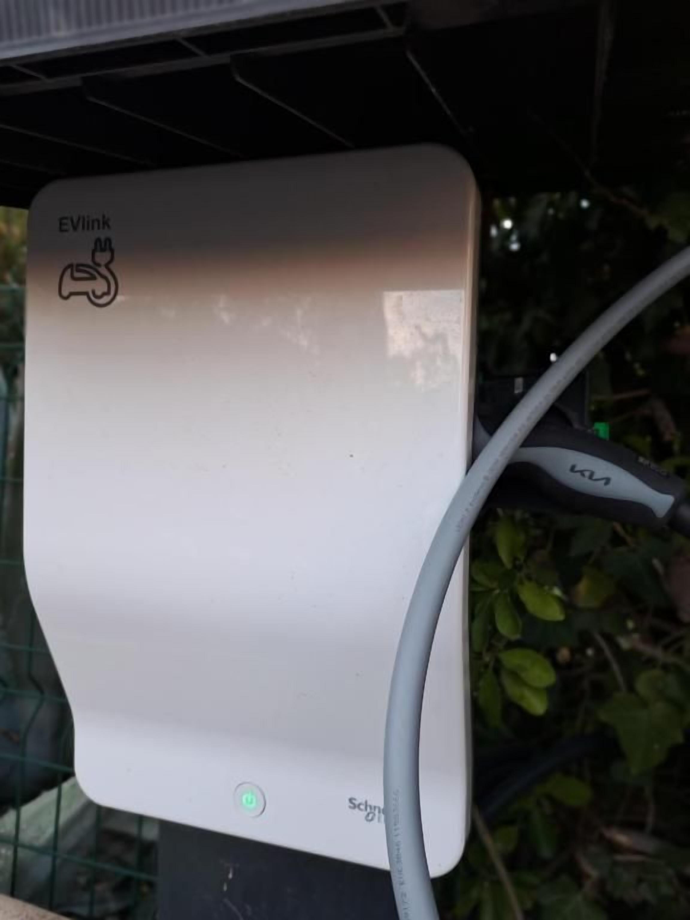 Una estación de carga EVlink blanca con un cable conectado.