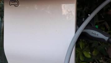 Una estación de carga EVlink blanca con un cable conectado.