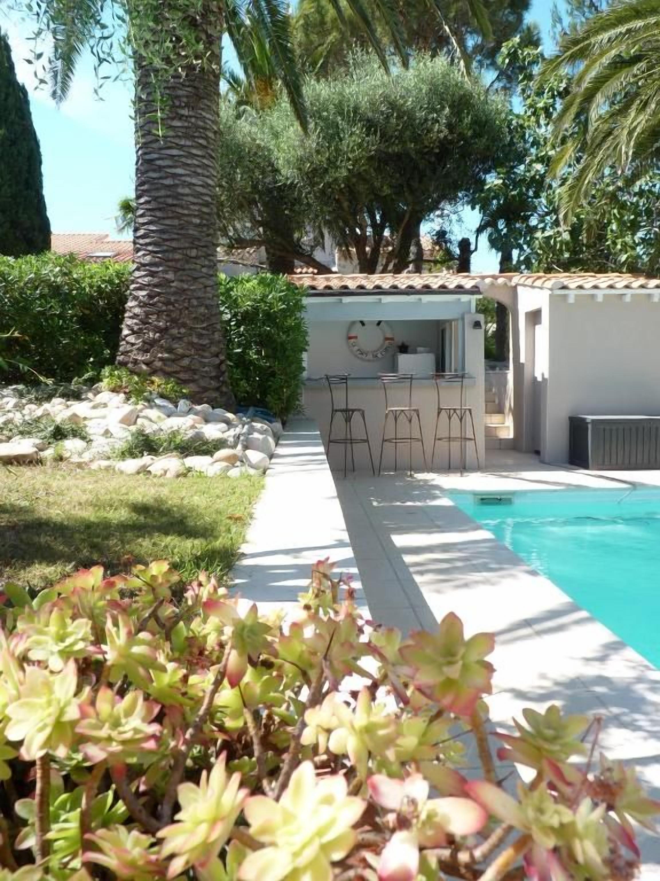 Zona de piscina con bar, asientos y vistas a la piscina.