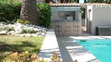 Zona de piscina con bar, asientos y vistas a la piscina.