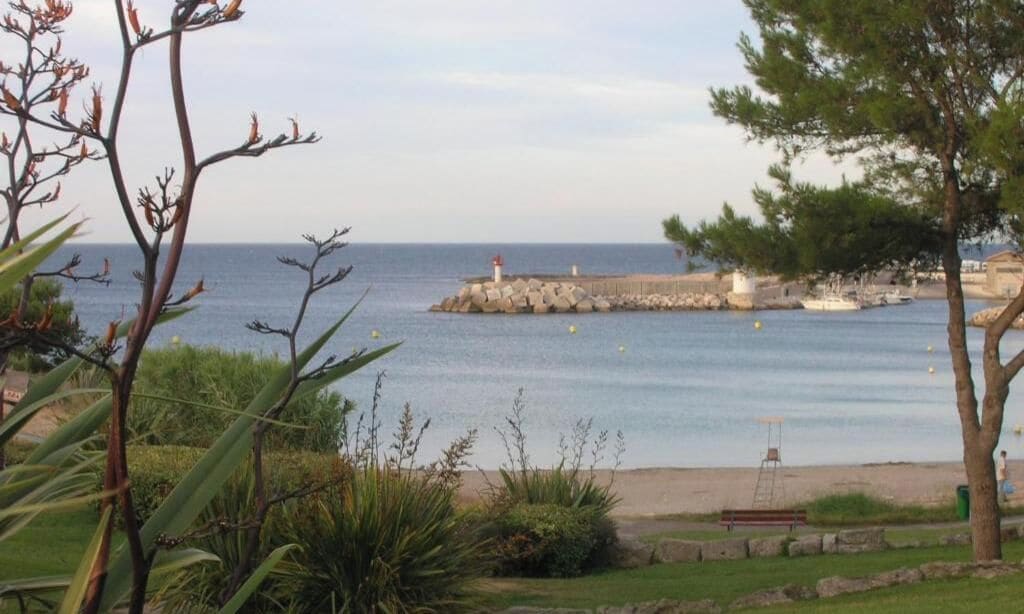 Paesaggio costiero con un faro, un molo e una spiaggia.