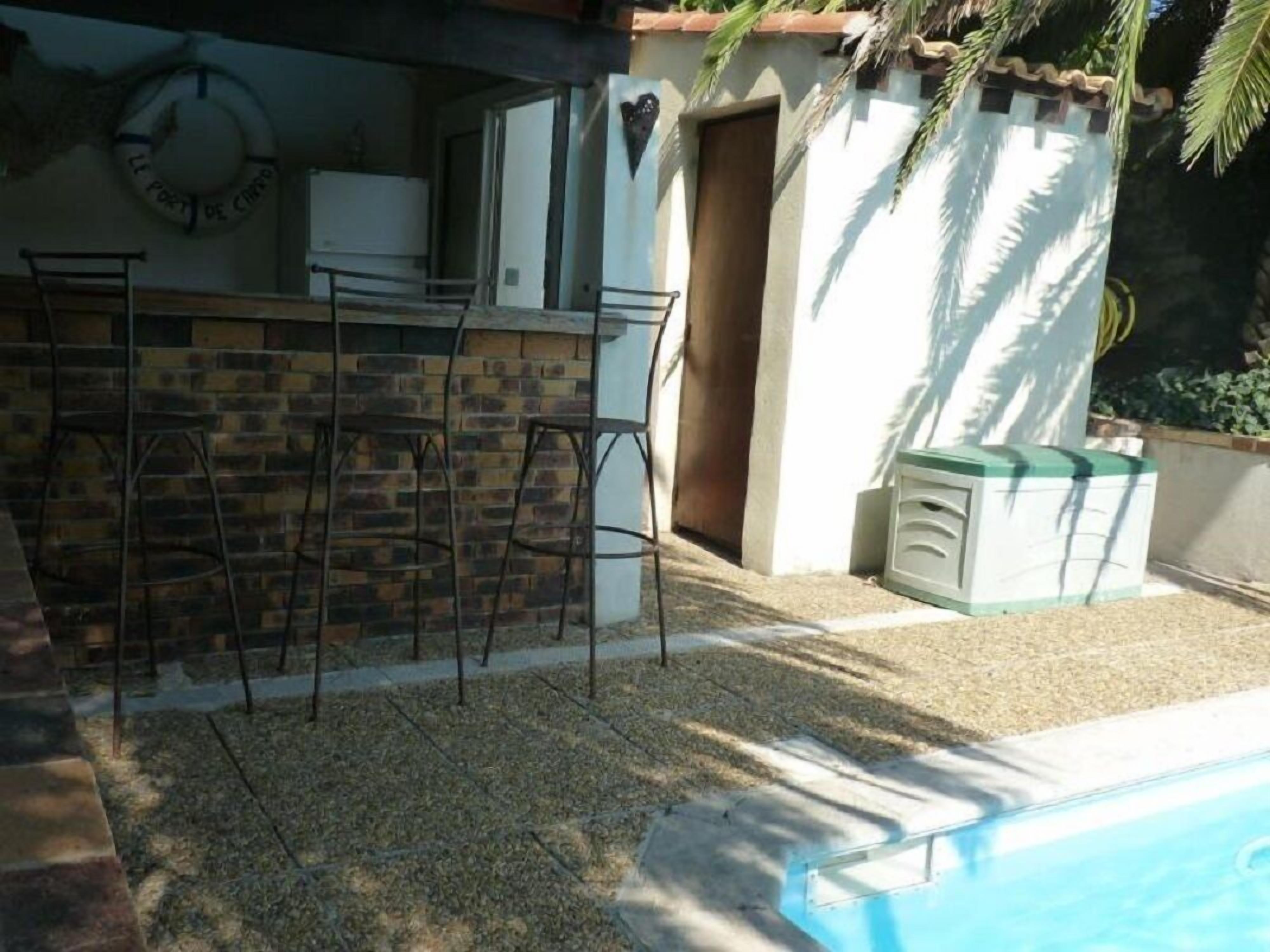 Un espace piscine agrémenté d’un mur en briques, d’une porte et d’une petite structure blanche aux bordures vertes.