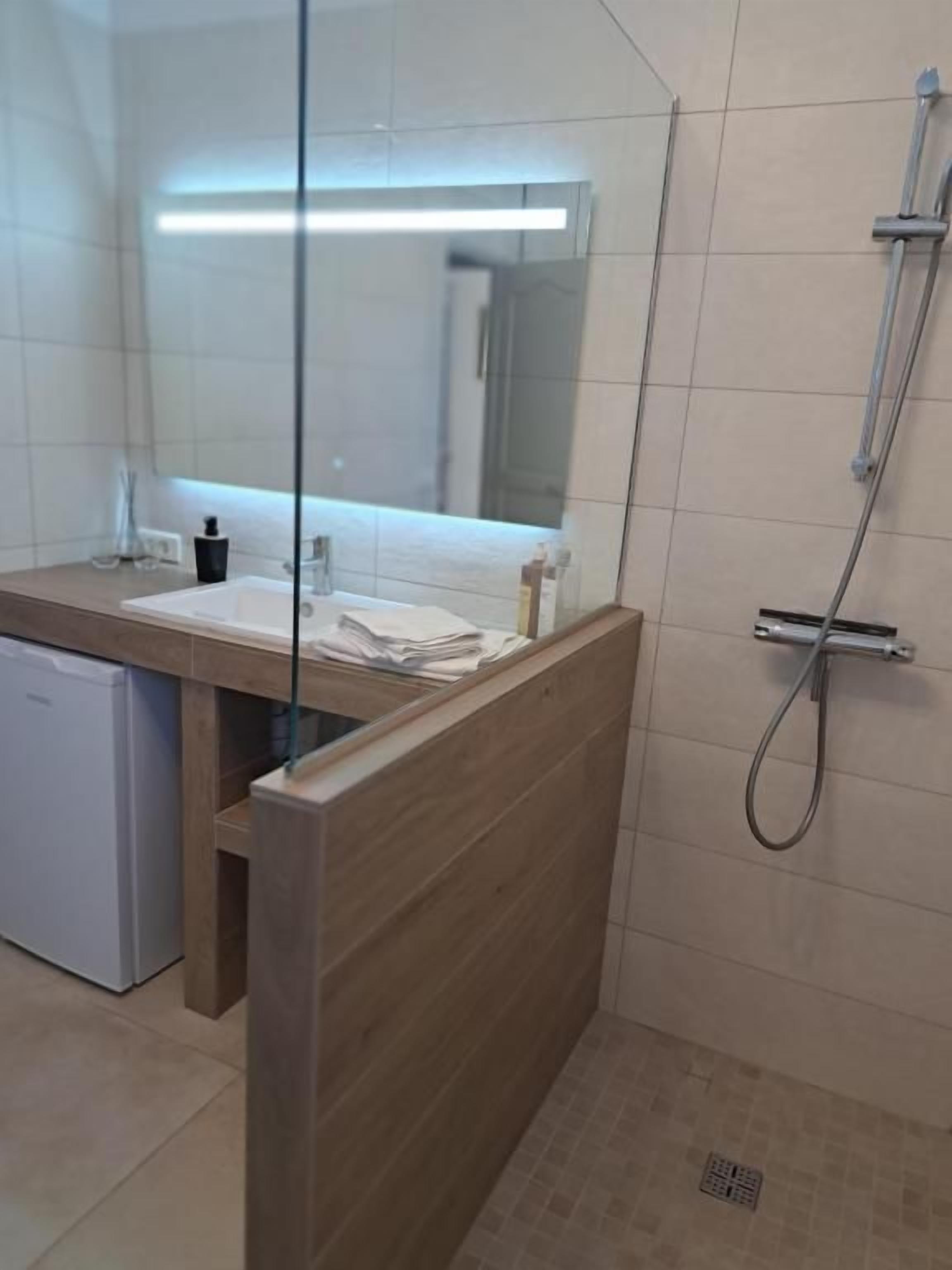 A modern bathroom with a glass partition, a shower, and a sink.