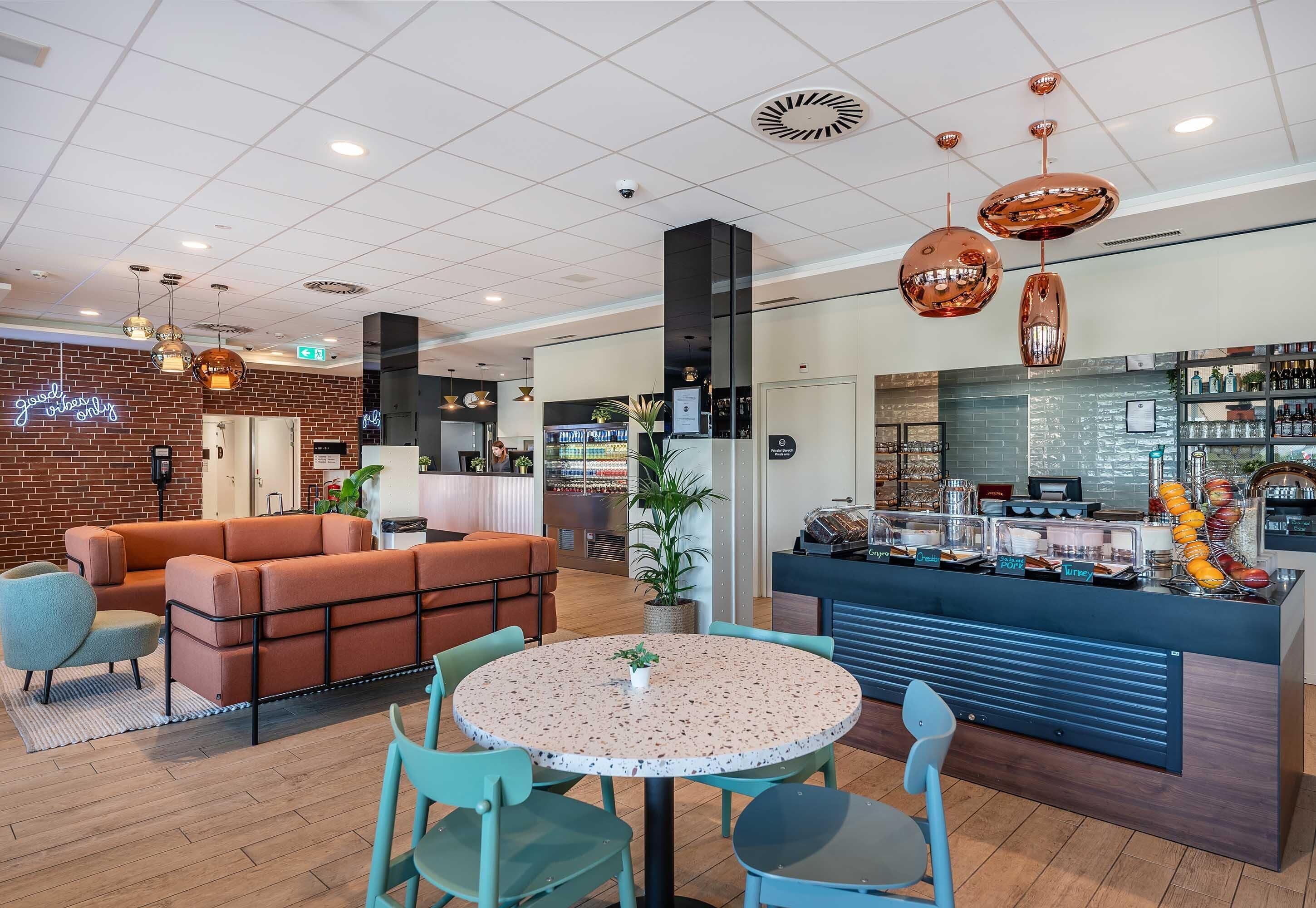 A modern interior with a seating area, a round table, and a counter with food items.