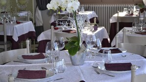 Un espace repas avec des tables rondes dressées pour le repas, agrémentées de nappes blanches et de serviettes violettes.