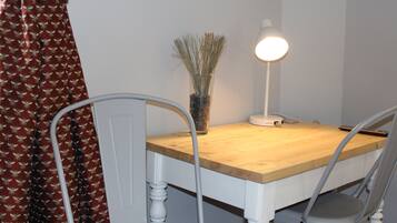 A dining table with chairs, a lamp, and a vase with dried plants.