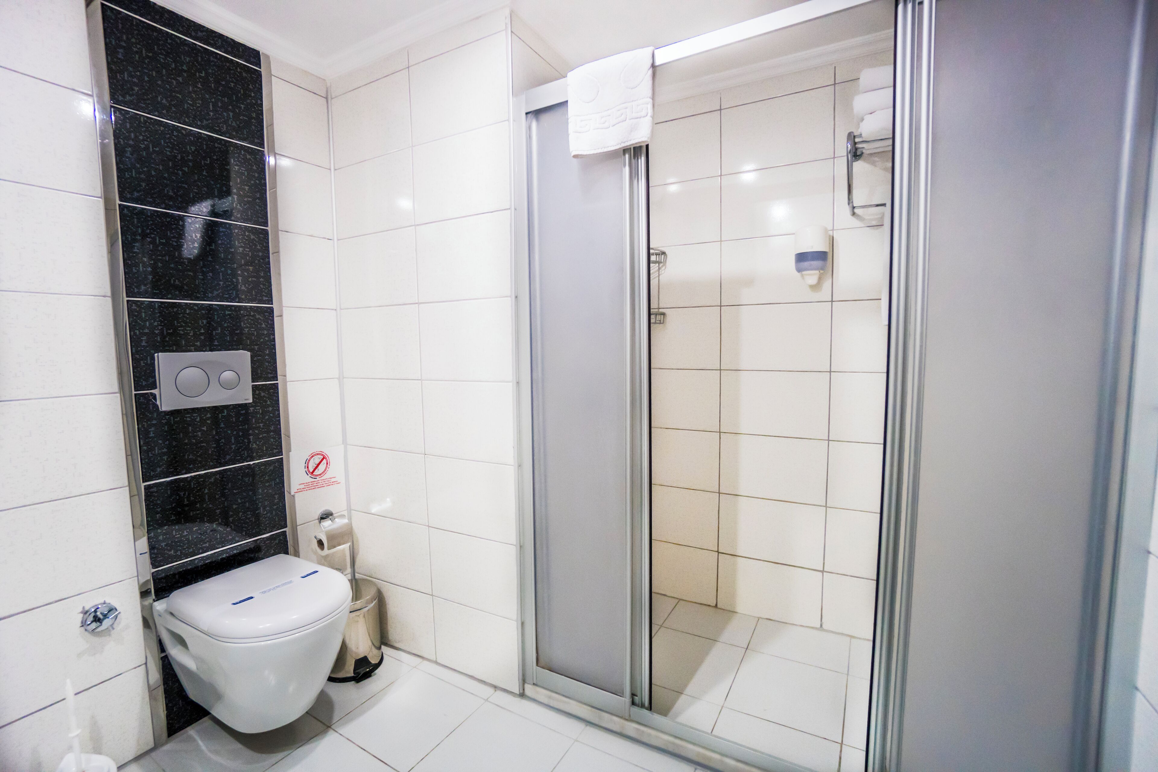 Une salle de bain équipée de toilettes, d’une douche et d’un sèche-mains.