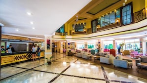 A spacious lobby with a reception desk, seating area, and a second-floor balcony with large windows. - Bieno Venus Hotel (Manavgat)