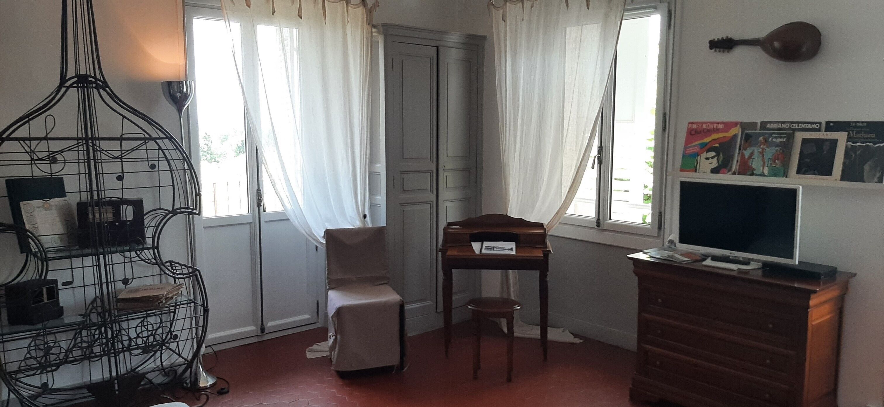 A room with a piano, a television, a bookshelf, and a window with curtains.