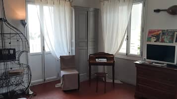 A room with a piano, a television, a bookshelf, and a window with curtains.