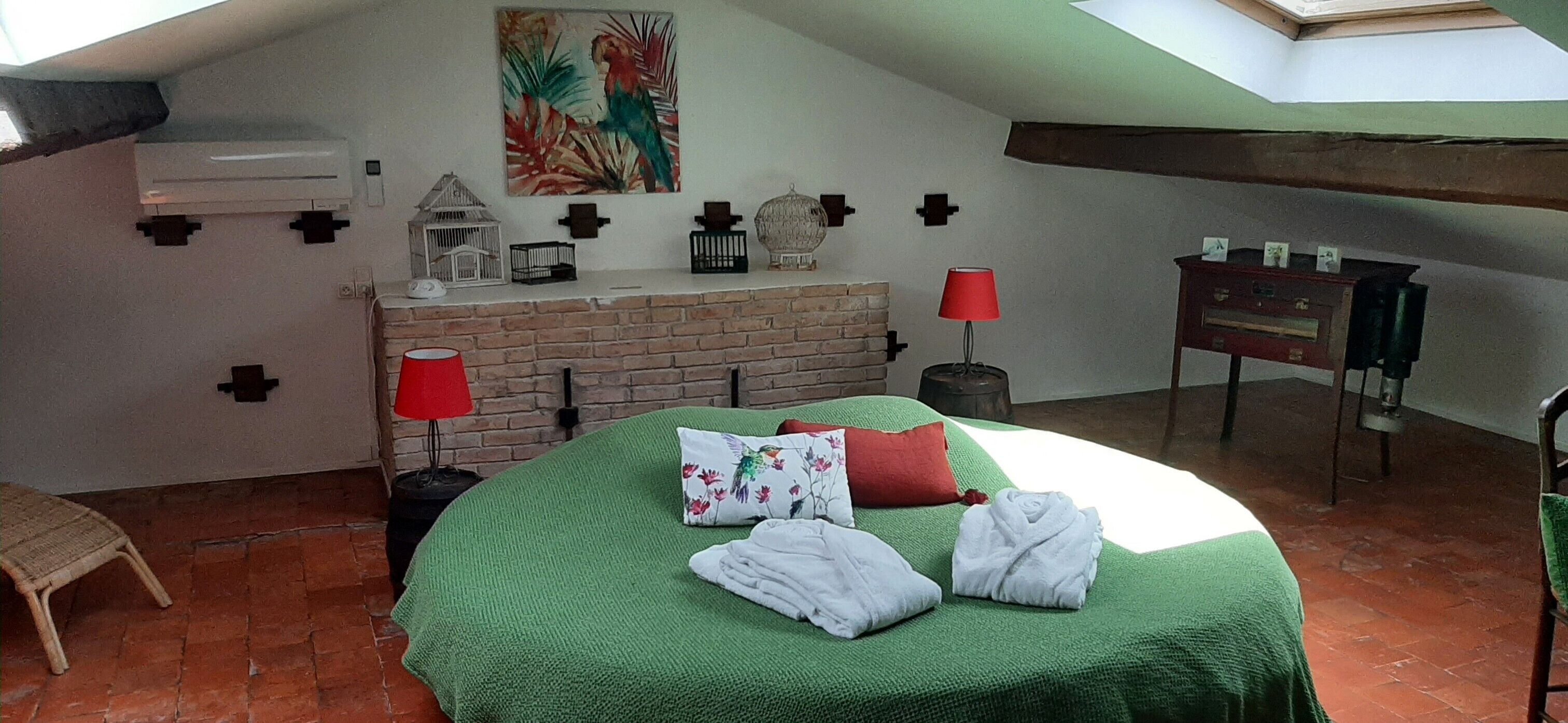 A cozy bedroom with a green bedspread, a red lamp, and a decorative wall.