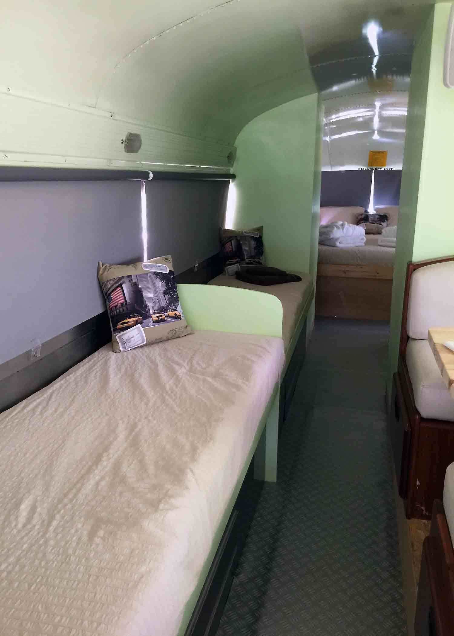 Een smalle, afgesloten ruimte met stapelbedden en een klein tafeltje, waarschijnlijk een slaapvertrek op een schip.