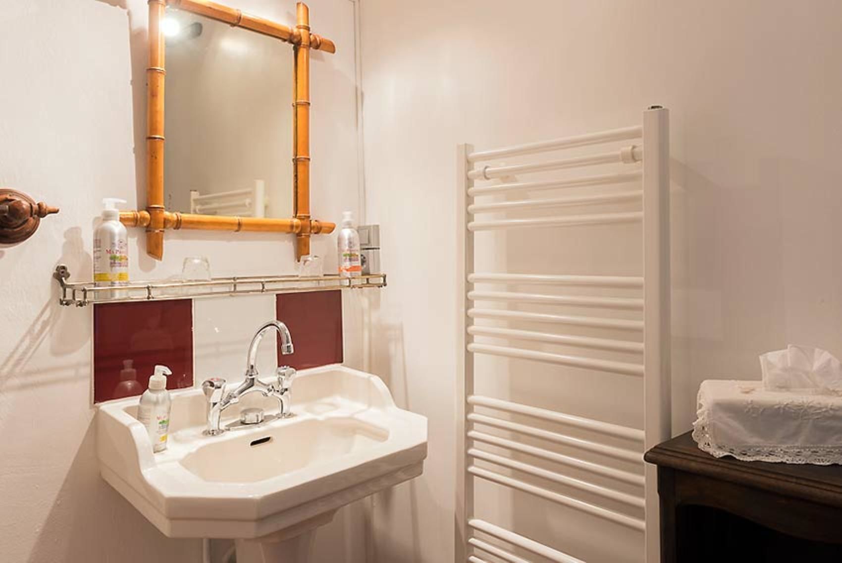 Un baño con lavabo, espejo y toallero.