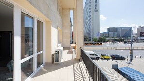 Ein Hotelbalkon mit großen Fenstern, Blick auf die Straße und ein hohes Gebäude mit der Aufschrift 'NOVEL'.