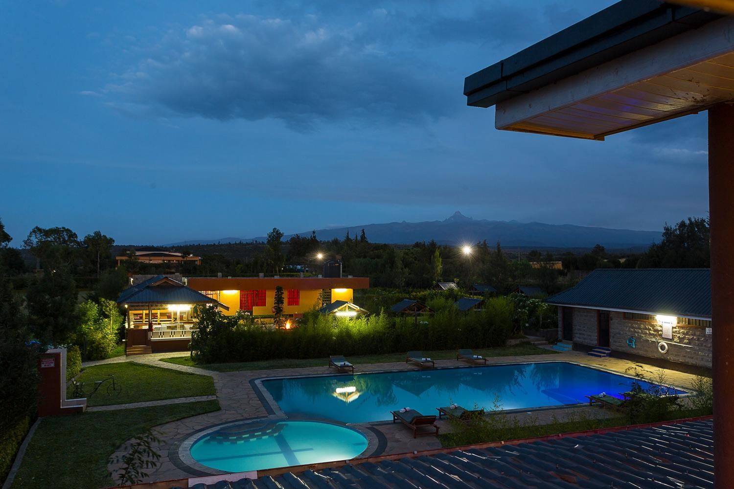 A residential property with a swimming pool, a covered patio, and a view of a mountain range.