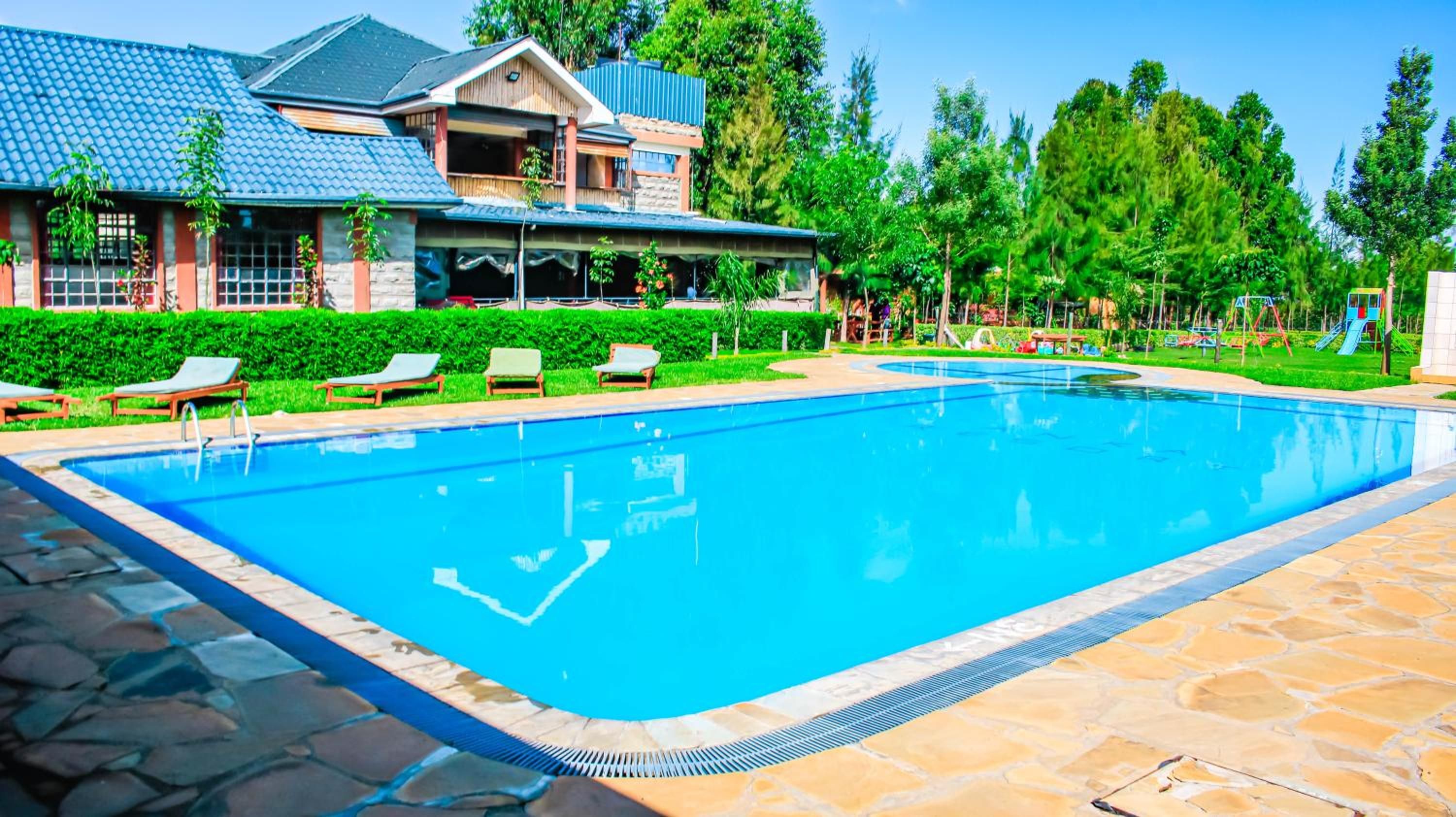 Una piscina con sillas de descanso, un camino de piedra y un edificio con techo de tejas.