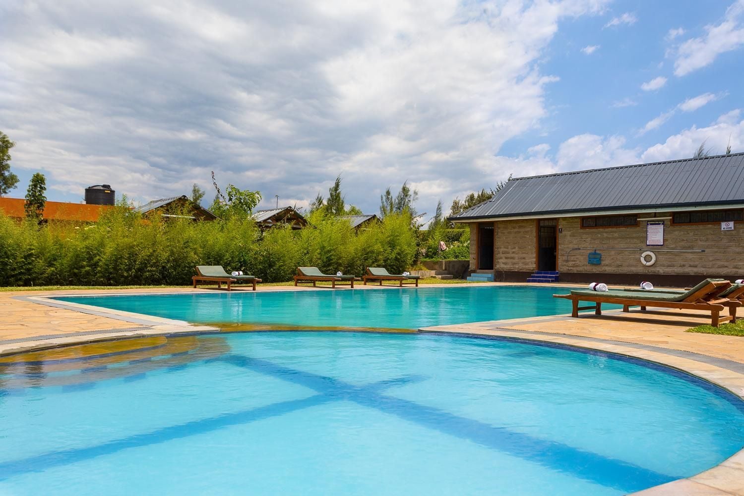 A swimming pool with lounge chairs and a building with a stone facade.