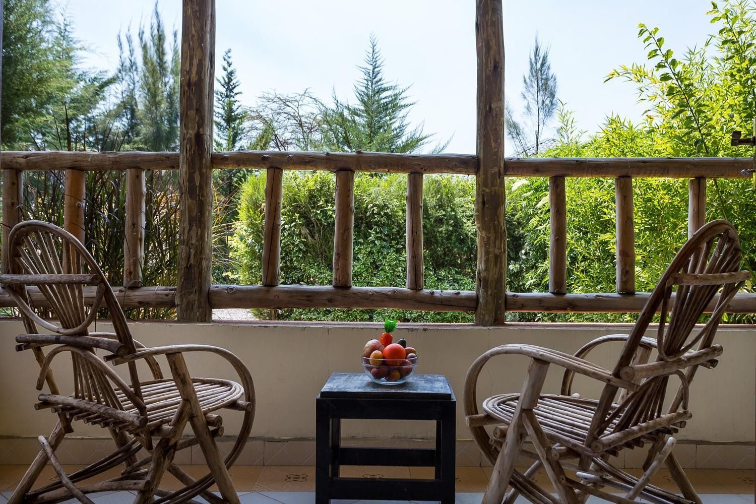 Ein Balkon mit zwei Korbstühlen und einem kleinen Tisch mit einer Obstschale.
