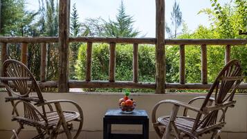 Un balcón con dos sillones de mimbre y una mesa pequeña con un frutero.