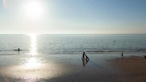 A beach with calm waters and a clear sky. - Garden Apartment On The Beach (Totland Bay)