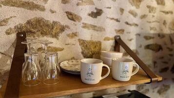 A wooden tray with wine glasses, plates, and branded mugs.