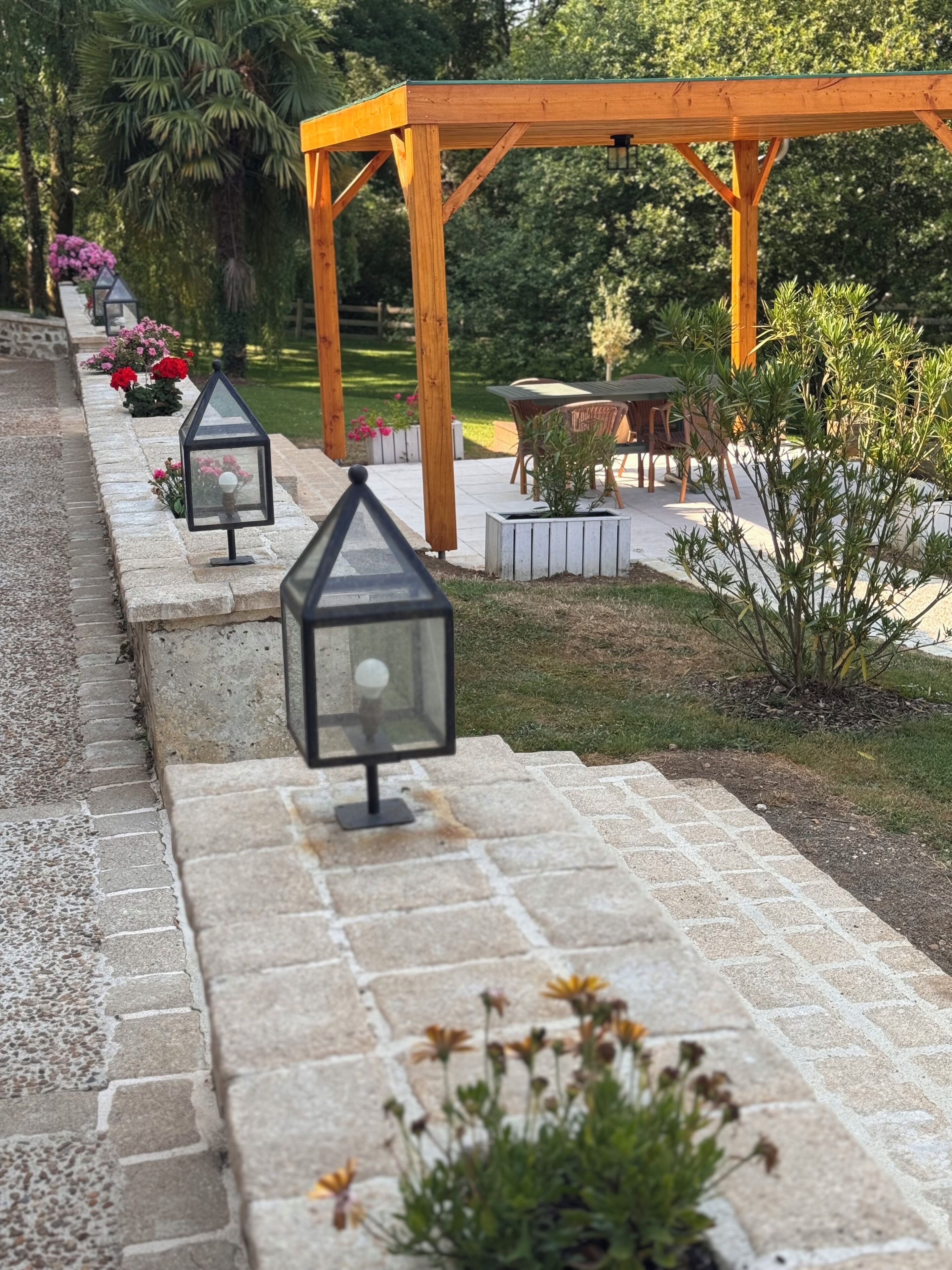 A stone pathway leading to a wooden pergola with outdoor seating.