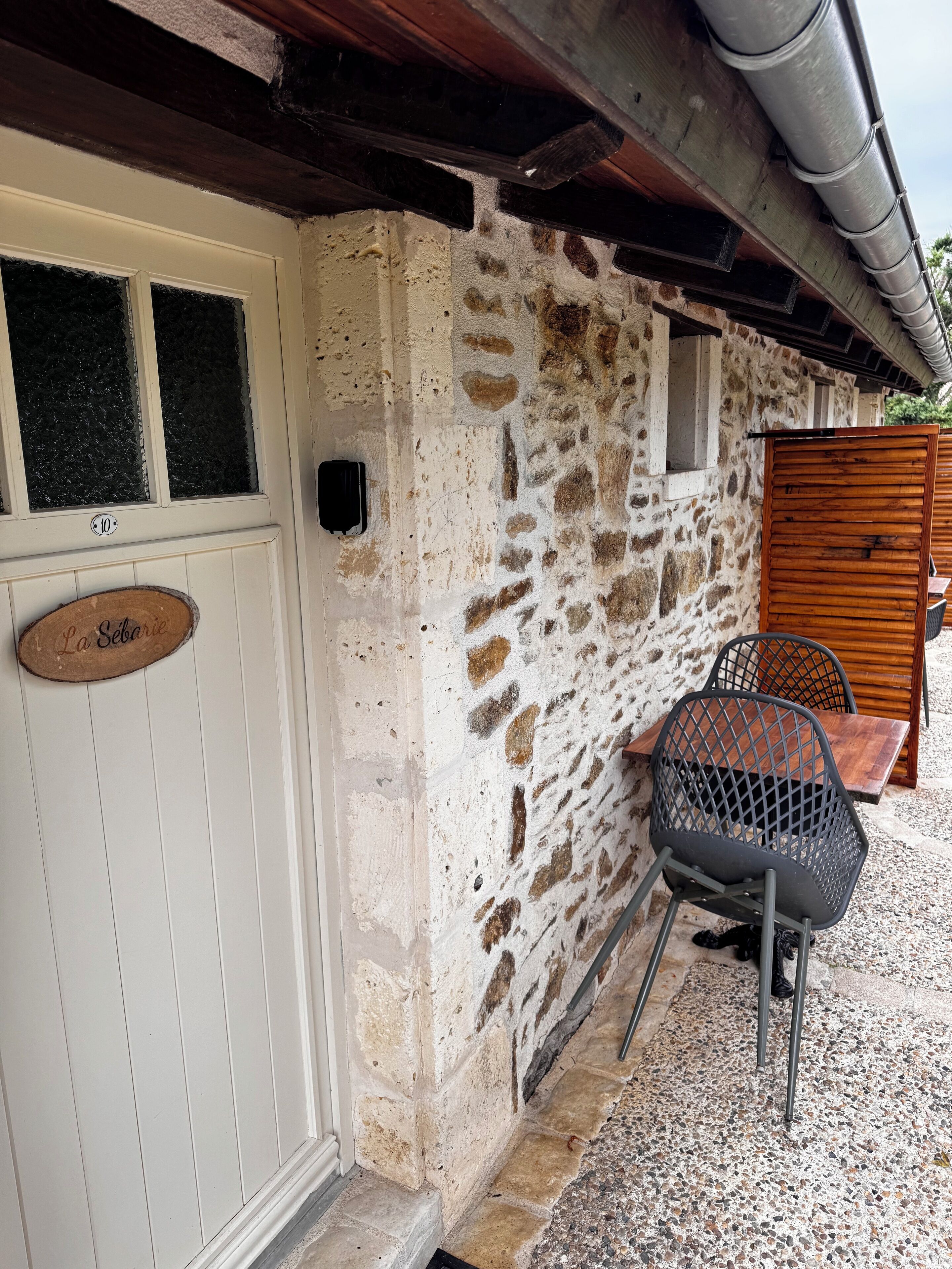 Un edificio rústico de piedra con una puerta de madera, un cartel que dice "La Seborga" y una mesa con sillas afuera.