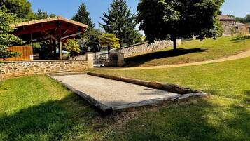 A park with a wooden pavilion, stone walls, and a grassy area with a concrete play structure.