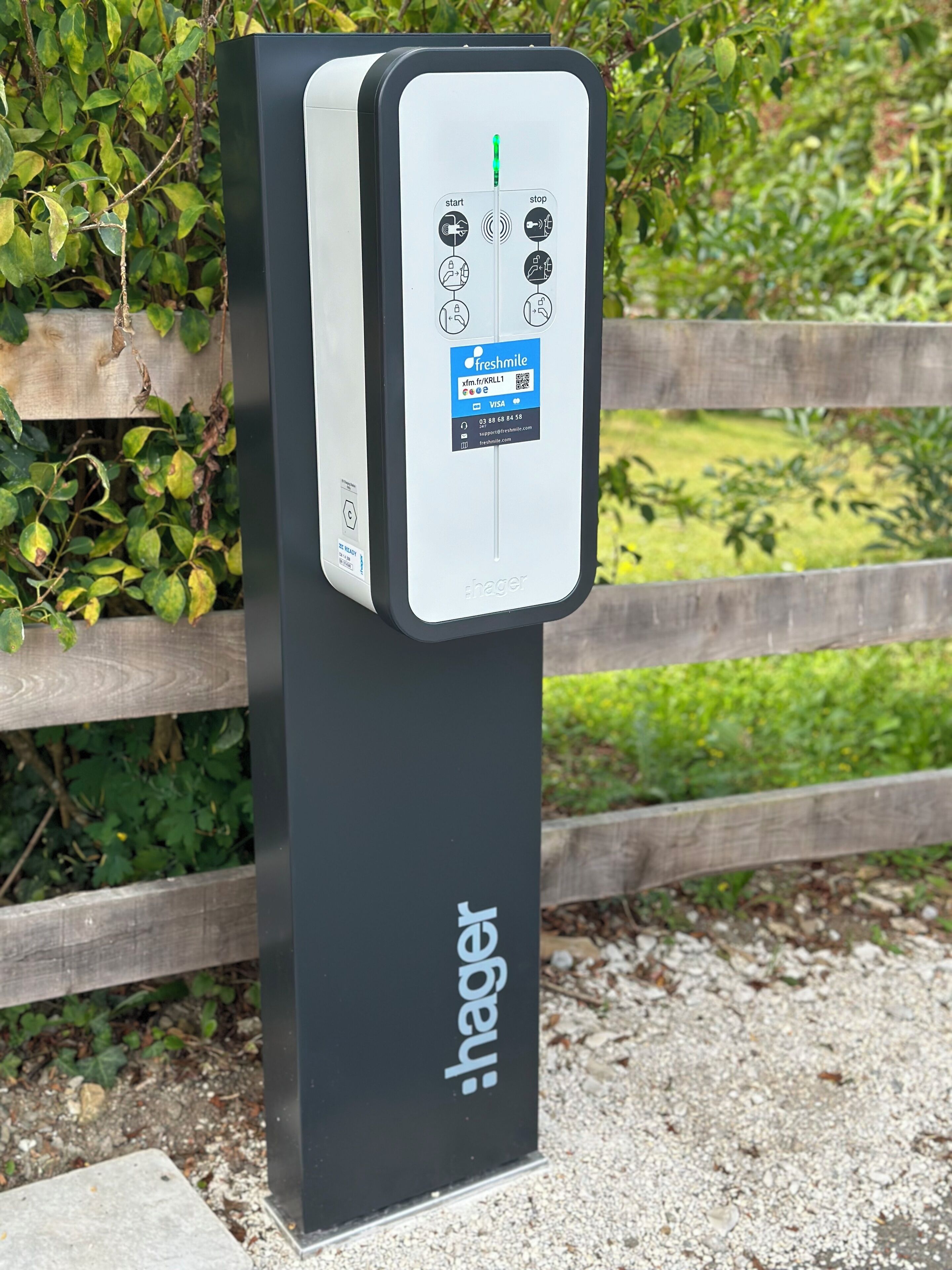 Uma estação de carregamento para veículos elétricos Hager, com código QR e informações de contacto.